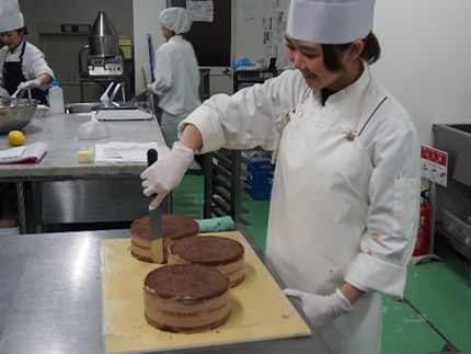 女性の職人さんがケーキを作っている様子の写真