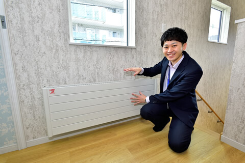 「ヒートポンプ温水暖房システム」の放熱パネルを説明する久野さん